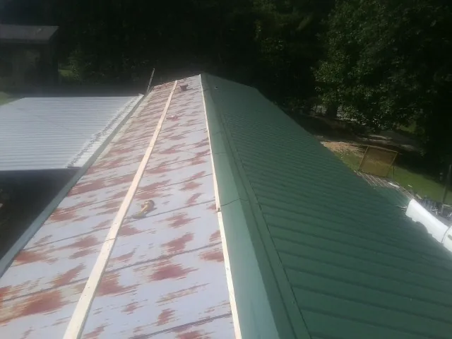Old rusted panels beside newly installed green metal roofing — Wind Damage Roof Repair by Roofing Brothers in Seven Mile