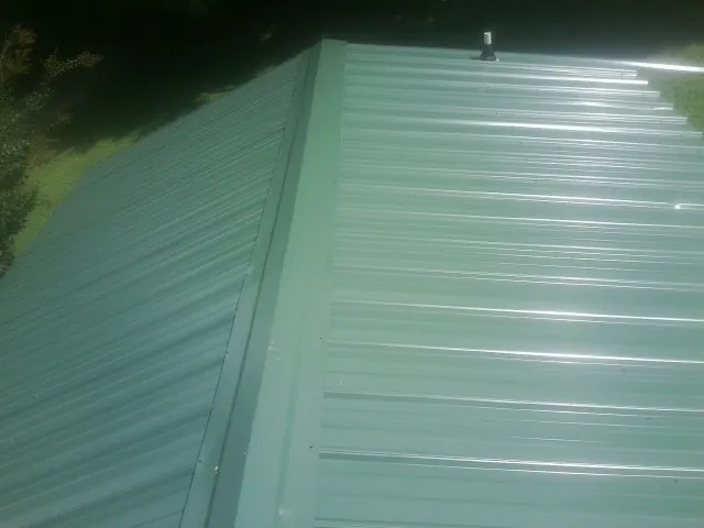 New green metal panels meeting at the ridge of a roof — Flat Roof Repair work by our crew in Seven Mile