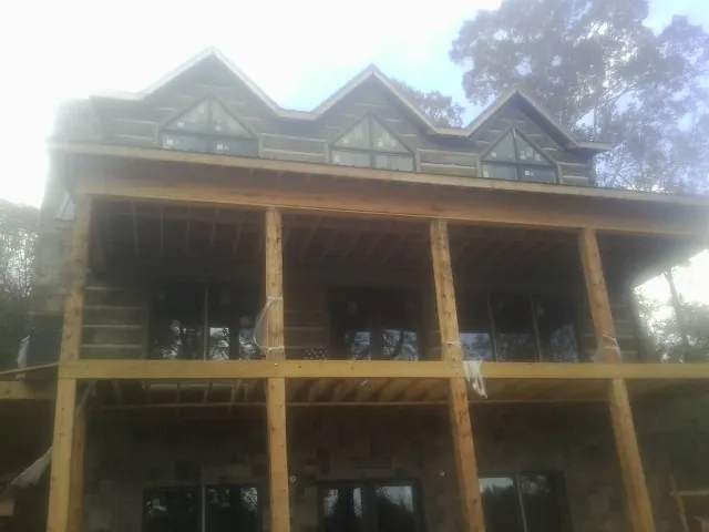 Dormers and porch framing on a large log home under construction — Roof Coating work by our crew in Seven Mile
