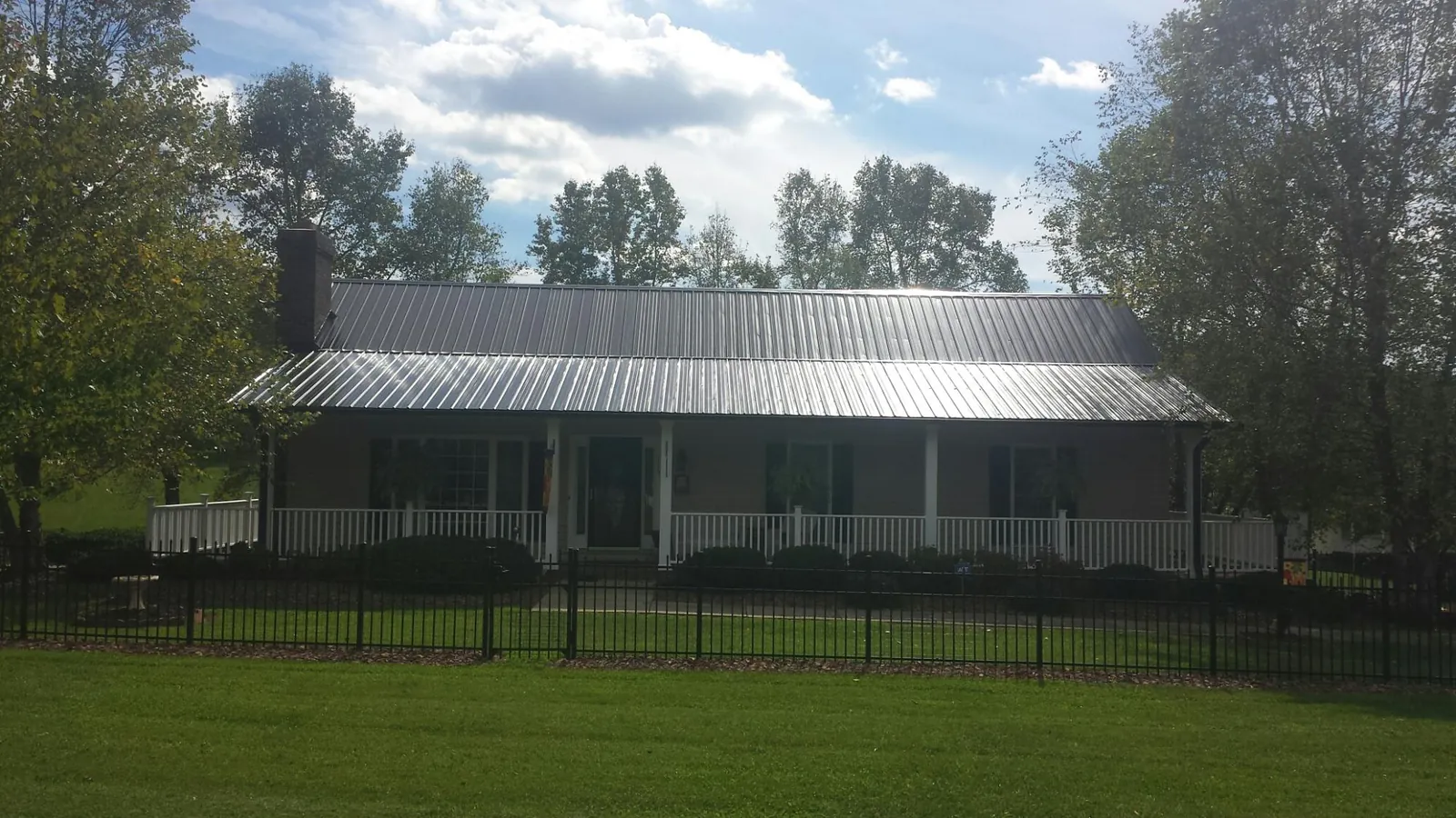 Gray metal roof on a brick ranch with a full width front porch — Gutter Guard Installation work by our crew in Seven Mile