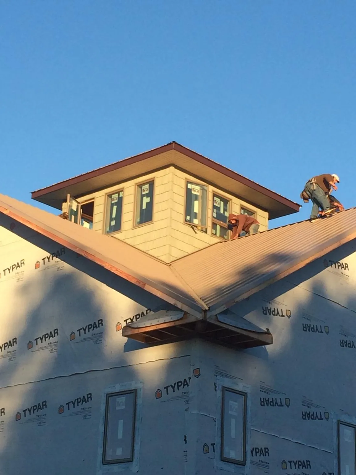 Roofers working around a rooftop cupola on a new metal roof at sunset — Roof Waterproofing in Seven Mile by Roofing Brothers
